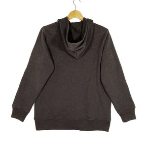 May include: A dark brown hooded sweatshirt with a drawstring hood. The sweatshirt has long sleeves and a ribbed hem and cuffs.