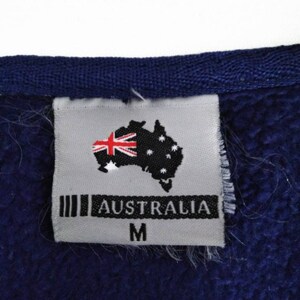 May include: A gray tag with the text "AUSTRALIA" and a stylized image of the Australian flag. The tag also has the letter "M" printed on it.