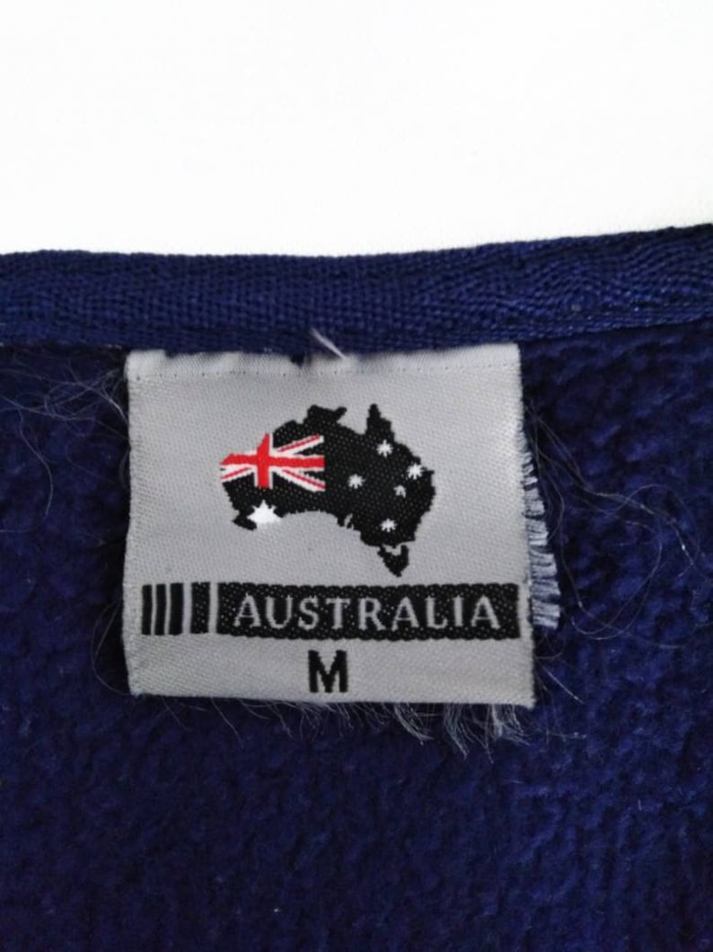 May include: A gray tag with the text "AUSTRALIA" and a stylized image of the Australian flag. The tag also has the letter "M" printed on it.