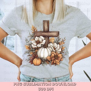 May include: A light gray t-shirt featuring a cross design with a white pumpkin, flowers, and fall foliage. The cross is brown, and the flowers are white and orange. The text "PNG SUBLIMATION DOWNLOAD" and "300 DPI" is at the bottom.
