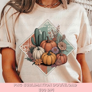 以下が含まれることがあります： ベージュ色のTシャツ。秋をテーマにしたグラフィックデザイン。オレンジと白のカボチャ、サボテン、花の要素が菱形に配置されています。「PNG SUBLIMATION DOWNLOAD 300 DPI」のテキストが下にあります。