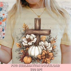 May include: A light yellow t-shirt featuring a cross, pumpkins, and flowers in a fall theme. The cross is brown, and the pumpkins are white and orange. The flowers are white and orange. The text "PNG SUBLIMATION DOWNLOAD 300 DPI" is at the bottom.