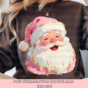 Op de afbeelding: Een bruine sweatshirt met een kleurrijk ontwerp van de kerstman. De kerstman heeft een roze muts, een witte baard en een lachend gezicht. Het ontwerp bevat gouden accenten en de tekst "PNG SUBLIMATION DOWNLOAD 300 DPI".