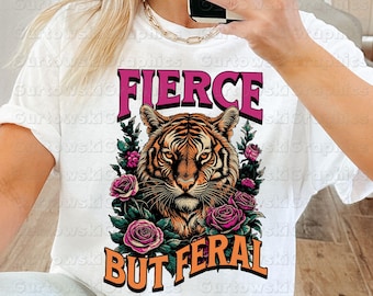 May include: White t-shirt with a pink and orange tiger graphic and the text "Fierce But Feral".