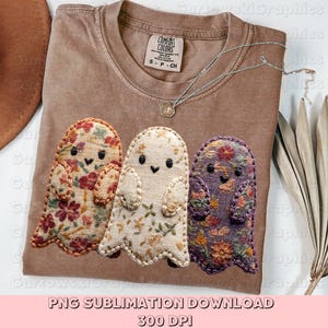 Puede incluir: Una camiseta marrón Comfort Colors con tres diseños de fantasmas bordados con estampados florales en rojo, crema y morado. Un collar plateado con un colgante descansa sobre la camisa. El texto "PNG SUBLIMATION DOWNLOAD 300 DPI" está en la parte inferior.