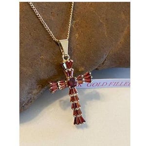 Op de afbeelding: Een gold-filled ketting met een rode granaat kruis hanger. Het kruis is versierd met baguette-vormige rode granaten.