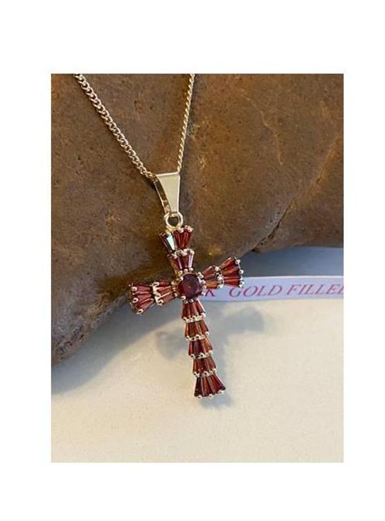 Op de afbeelding: Een gold-filled ketting met een rode granaat kruis hanger. Het kruis is versierd met baguette-vormige rode granaten.