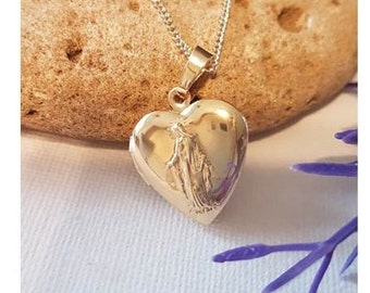 Op de afbeelding: Een gouden ketting met een hartvormige hanger en een delicate ketting. De hanger heeft een reliëf van een vrouw die een kind vasthoudt.