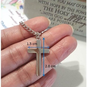 Puede incluir: Collar con colgante de cruz de plata con cadena. La cruz mide 1,5 cm de ancho y 2,8 cm de largo.