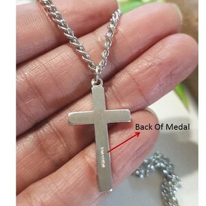 Puede incluir: Collar de cadena de plata con un colgante de cruz de plata. La parte posterior del colgante de cruz tiene la inscripci&oacute;n "Made in China".