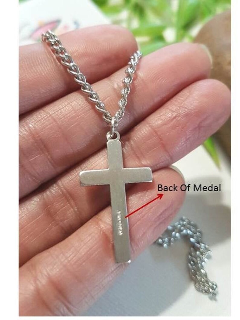 Puede incluir: Collar de cadena de plata con un colgante de cruz de plata. La parte posterior del colgante de cruz tiene la inscripci&oacute;n "Made in China".
