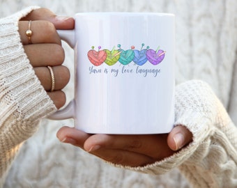 May include: White ceramic mug with a colorful yarn heart design and the text "Yarn is my love language".