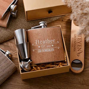 May include: A wooden gift box set with a personalized stainless steel flask, a shot glass, and a bottle opener. The flask is engraved with the name "Heather" and the text "EST. 2012 GROOMSMAN". The bottle opener is engraved with the text "EVEN GROOMSMAN EST. 20.12.2023".