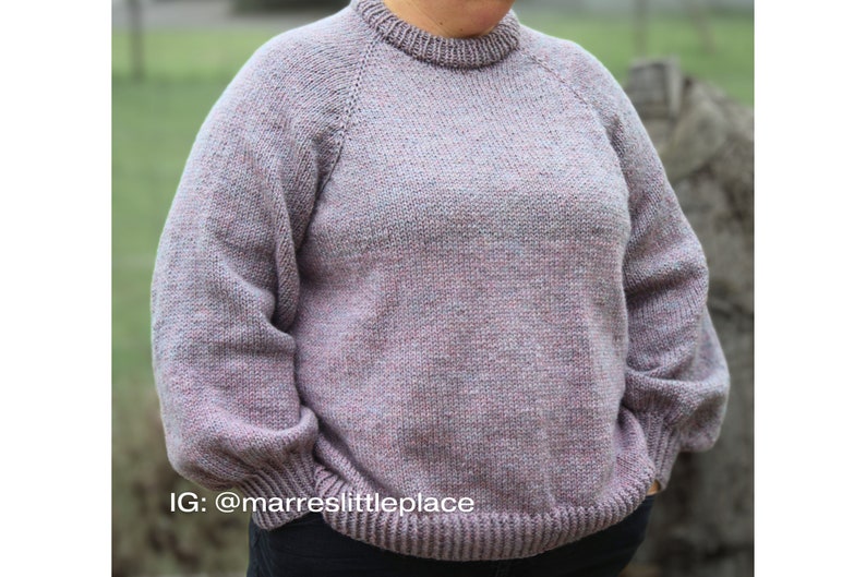 May include: A soft, light purple sweater with a crew neck and long sleeves. The sweater has a subtle speckled pattern and a ribbed hem and cuffs.