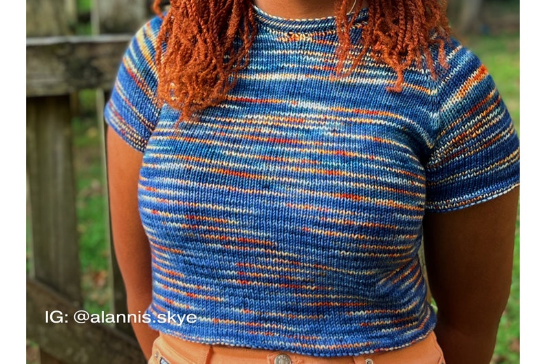 A relaxed fit knitted tee knitting in blue, orange, and white yarn worn on a female model outside.