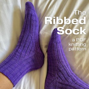 May include: A pair of purple ribbed knit socks on a white background. The text "The Ribbed Sock" and "a PDF knitting pattern" is written in white on the image.