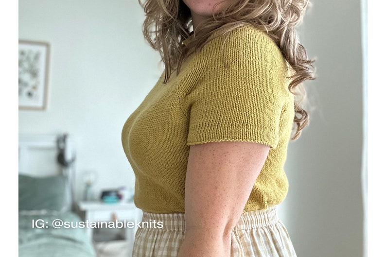 A relaxed fit knitted tee knitting in dull yellow  DK weight yarn worn on a female model and tucked into a gingham checked skirt.