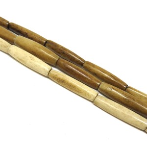 May include: A strand of natural bone beads, with alternating light and dark brown colours. The beads are cylindrical and have a smooth, polished finish.