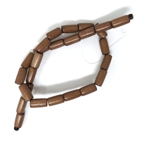 May include: A brown wooden beaded necklace with a knotted string. The beads are cylindrical and have a smooth finish.