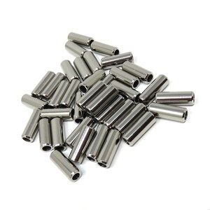 May include: A collection of shiny, cylindrical metal tubes with a polished finish. Each tube has a hollow center and is approximately 1 inch in length. The tubes are scattered on a white background, creating a clean and industrial aesthetic.