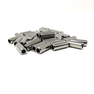 May include: A pile of shiny, silver-colored metal tubes with a cylindrical shape. Each tube has a hole at both ends. The objects are scattered on a white background, creating a clean and simple aesthetic.