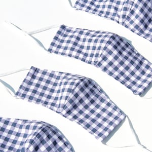 May include: Four purple and white gingham fabric face masks with white elastic straps.