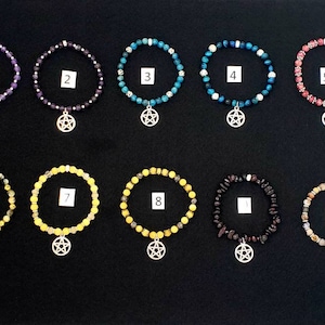 May include: Ten bracelets with different colored beads and a silver pentagram charm. The bracelets are numbered 1 through 10.