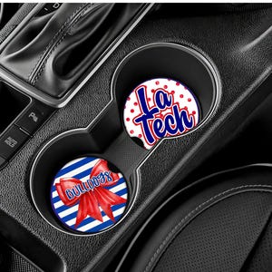 May include: Two circular car cup holder coasters featuring red, white, and blue designs. One coaster displays the text La Tech in blue with a red outline on a white background with red dots. The other features a red bow and the word Bulldogs.