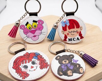 Llaveros de piel sintética de la Academia MCA Mount Carmel con la mascota de la clase: Pantera, Muñeca de Ragdoll o Mariposa.
