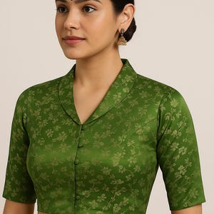 Op de afbeelding: Groene blouse met bloemenprint, reverskraag en korte mouwen. De knoopsluiting en het bloemmotief geven een vleugje elegantie. De stof heeft een lichte glans.