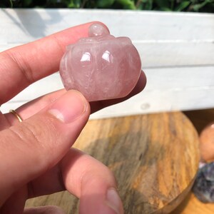 May include: A small, pink, carved rose quartz box with a lid. The box is in the shape of a pumpkin.
