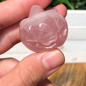 May include: A carved pink rose quartz pumpkin. The pumpkin is approximately 5 cm tall and has a smooth, polished surface.