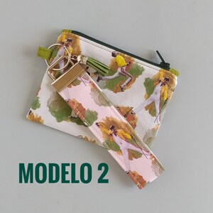 May include: A small zippered pouch and wristlet with a repeating pattern of a performer in a yellow jacket and white pants. The wristlet has a gold-colored clasp and a green tassel. The text "MODELO 2" is printed in green.