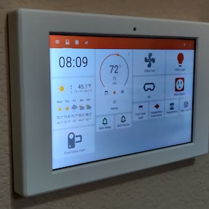 Puede incluir: Una pantalla táctil de pared blanca con una interfaz naranja y blanca. La pantalla muestra la hora 08:09, la temperatura 72 grados Fahrenheit y el pronóstico del tiempo para la semana. La pantalla también muestra iconos para controlar las luces, los ventiladores y otras funciones de automatización del hogar.
