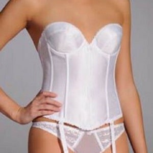 May include: White strapless corset with a sweetheart neckline, paired with matching lace underwear and garter straps. The lingerie set is made of a smooth, satin-like fabric.