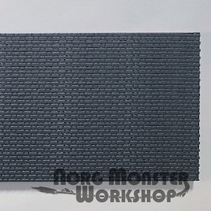 May include: A close-up of a dark gray brick wall texture. The wall is made of small, rectangular bricks with a rough surface. The bricks are arranged in a staggered pattern.