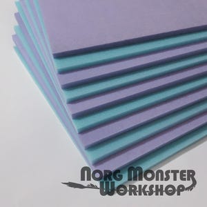 May include: A pile of foam sheets in alternating shades of lilac and turquoise. The sheets are stacked, showing the edges, creating a layered appearance. The text "norg Monster WORKSHOP" is visible at the bottom.