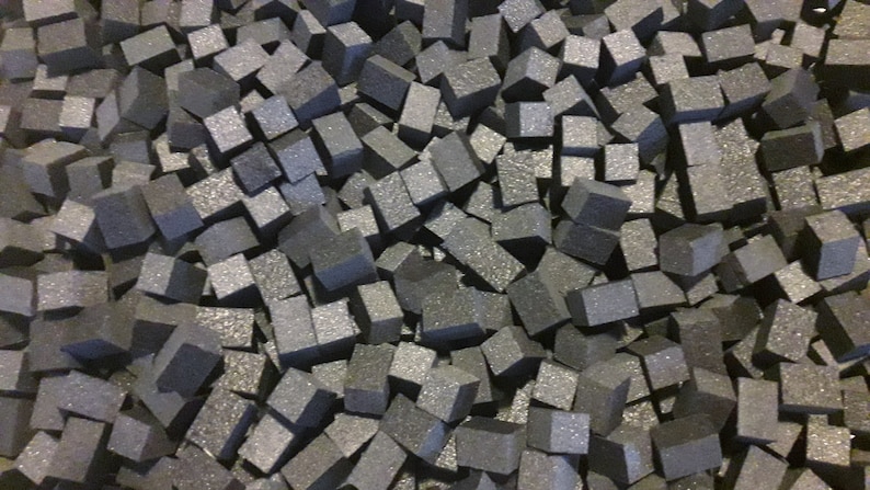 May include: A close-up image of a pile of small, gray, foam cubes. The cubes are all roughly the same size and shape, and they are arranged in a random pattern.