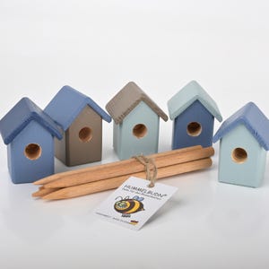 Könnte beinhalten: Fünf Miniatur-Vogelhäuschen aus Holz in Blautönen, Grau und Braun, mit einem kleinen Loch für den Einstieg der Vögel. Die Vogelhäuschen sind in einer Reihe angeordnet und werden mit vier Holzstiften zum Befestigen geliefert.