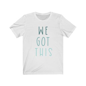 Puede incluir: Camiseta blanca con el texto "WE GOT THIS" impreso en un degradado azul y verde.