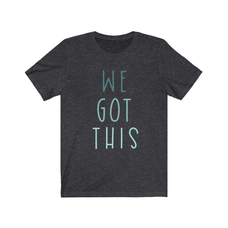 Puede incluir: Camiseta gris oscuro jaspeada con el texto "WE GOT THIS" en azul claro.