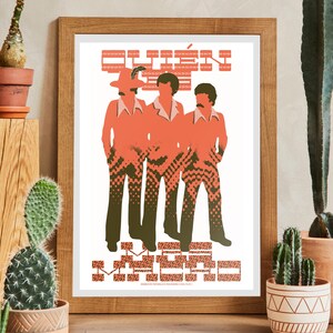 May include: A framed print featuring a retro illustration of three figures in orange suits and patterned pants. The print has text at the top and bottom in a pixelated style. The artwork is displayed in a wooden frame.