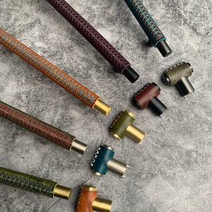 Pode incluir: Conjunto de puxadores de armário envoltos em couro em várias cores, incluindo marrom, verde, azul-petróleo e bordô. Os puxadores têm vários acabamentos, incluindo latão e preto.