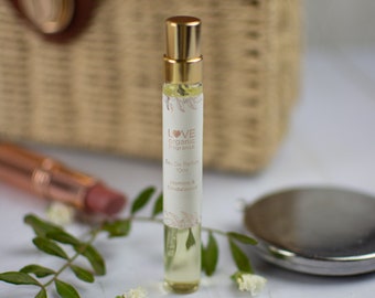 May include: A small, clear glass bottle of Love Organic Fragrance Eau de Parfum in Jasmine & Sandalwood. The bottle has a gold cap and a white label with the brand name and scent.