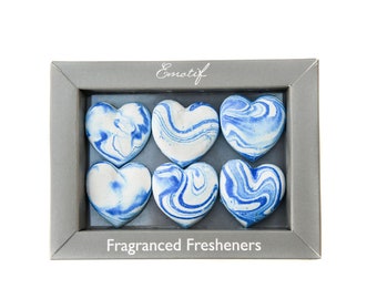 May include: A gray box with the word "Emotif" printed on the top. The box contains six blue and white marbled heart-shaped air fresheners. The text "Fragranced Fresheners" is printed on the bottom of the box.