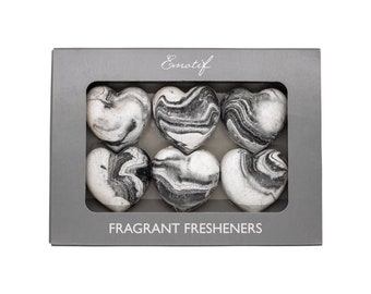 May include: A box of six black and white marbled heart-shaped fragrant fresheners. The box is gray and has the word "Emotif" printed on the top. The text "Fragrant Fresheners" is printed on the bottom of the box.