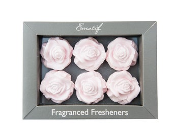 May include: A box of six pink rose-shaped air fresheners. The box is gray with the text "Emotif" and "Fragranced Fresheners" printed on it.