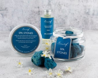 May include: A glass jar filled with blue spa stones. The jar has a white label that reads "Emotif SPA STONES". There is a smaller jar with a white label that reads "Emotif SPA STONES" and a small bottle of essential oil with a white label that reads "Emotif Concentrated diffuser oil 100ml SPA STONES".
