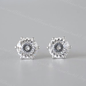 May include: A pair of silver stud earrings with clear round cubic zirconia stones.