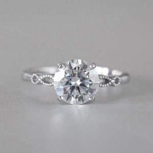 Könnte beinhalten: Ein silberner Verlobungsring mit einem großen, runden, klaren Diamanten. Die Ringschiene ist mit einem zarten, gedrehten Design verziert.